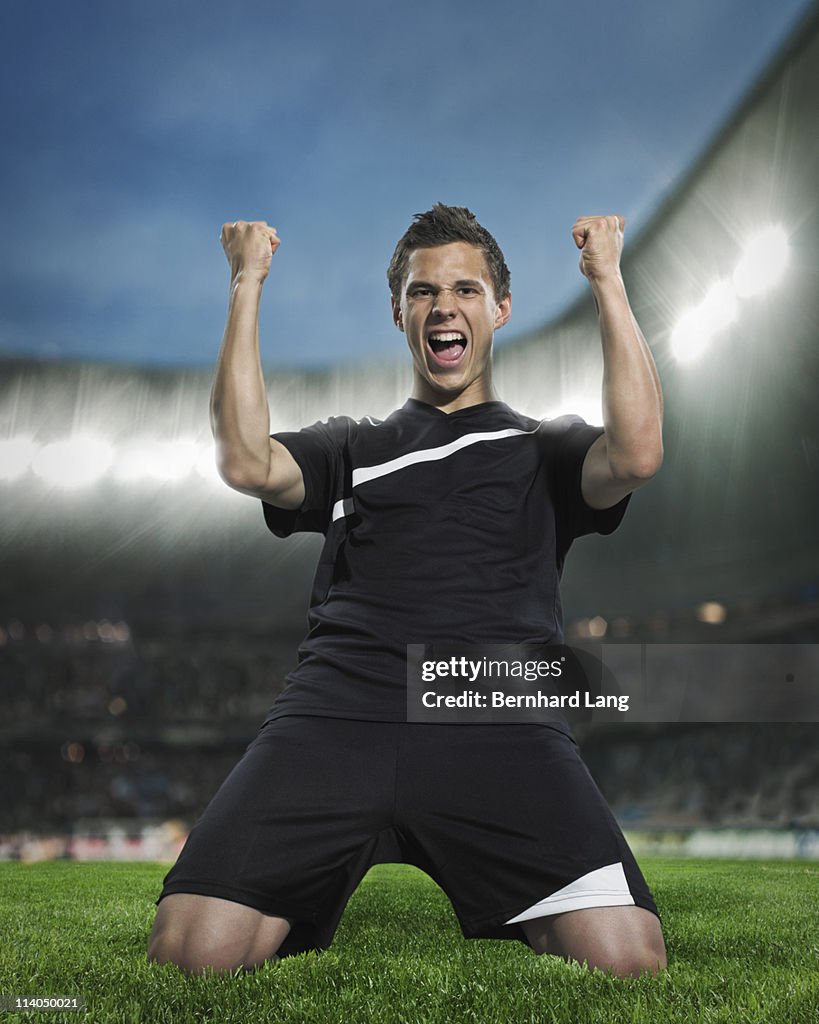 Soccer player on his knees celebrating in stadium