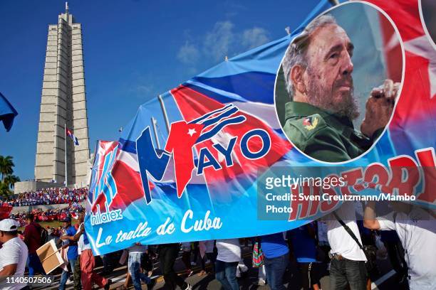 Cubans carry a banner with the image of late Revolution leader Fidel Castro as they pass in front of the Jose Marti monument during the May Day...