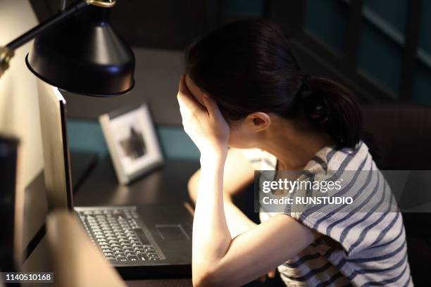 tired woman with head in hand on desk at home - matt japan stock-fotos und bilder