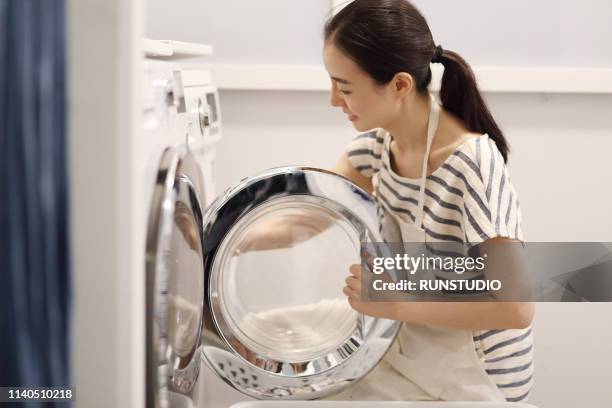 woman washing cloth with washing machine - lady washing machine stock pictures, royalty-free photos & images