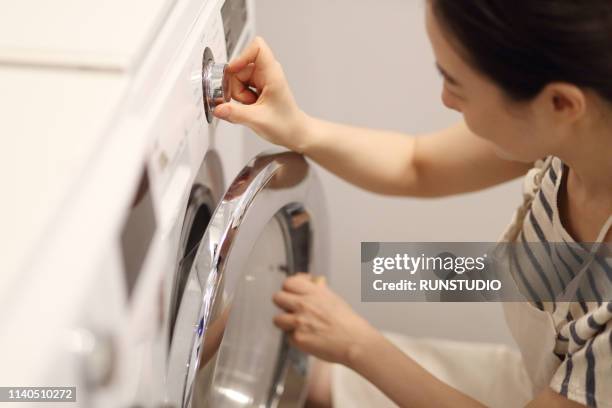 woman turning washing machine dial - turn dial stock pictures, royalty-free photos & images