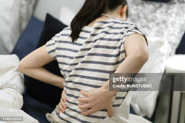 woman with backache in bedroom - back pain bed stock pictures, royalty-free photos & images