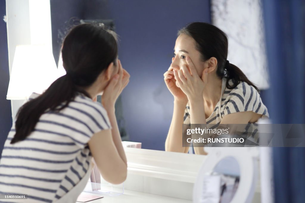 Woman checking face in mirror