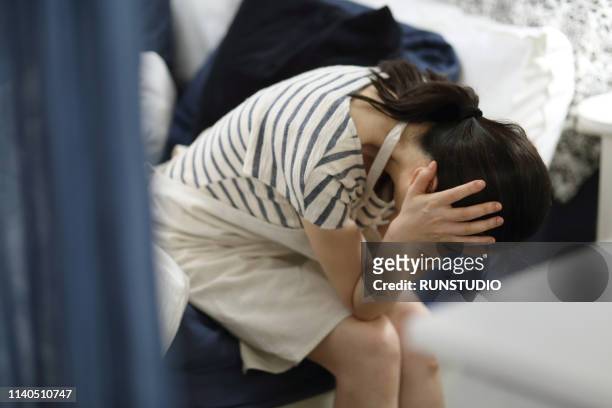 woman with headache in bedroom - stay at home mother stockfoto's en -beelden