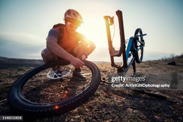 mountain biker repairing a flat tire. - encher atividade imagens e fotografias de stock
