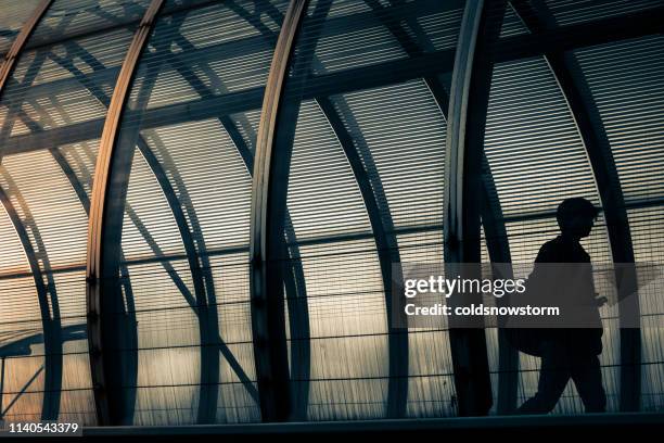 silhouette man walking alone through futuristic urban tunnel in the city - metal catwalk stock pictures, royalty-free photos & images