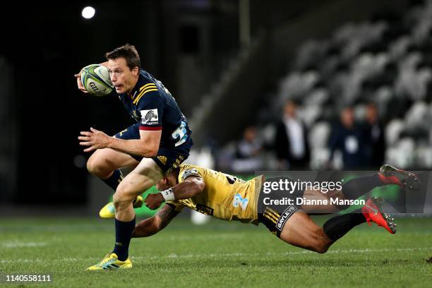 Ben Smith of the Highlanders is tackled by Matt Proctor of the Hurricanes during the round 8 Super Rugby match between the Highlanders and Hurricanes...