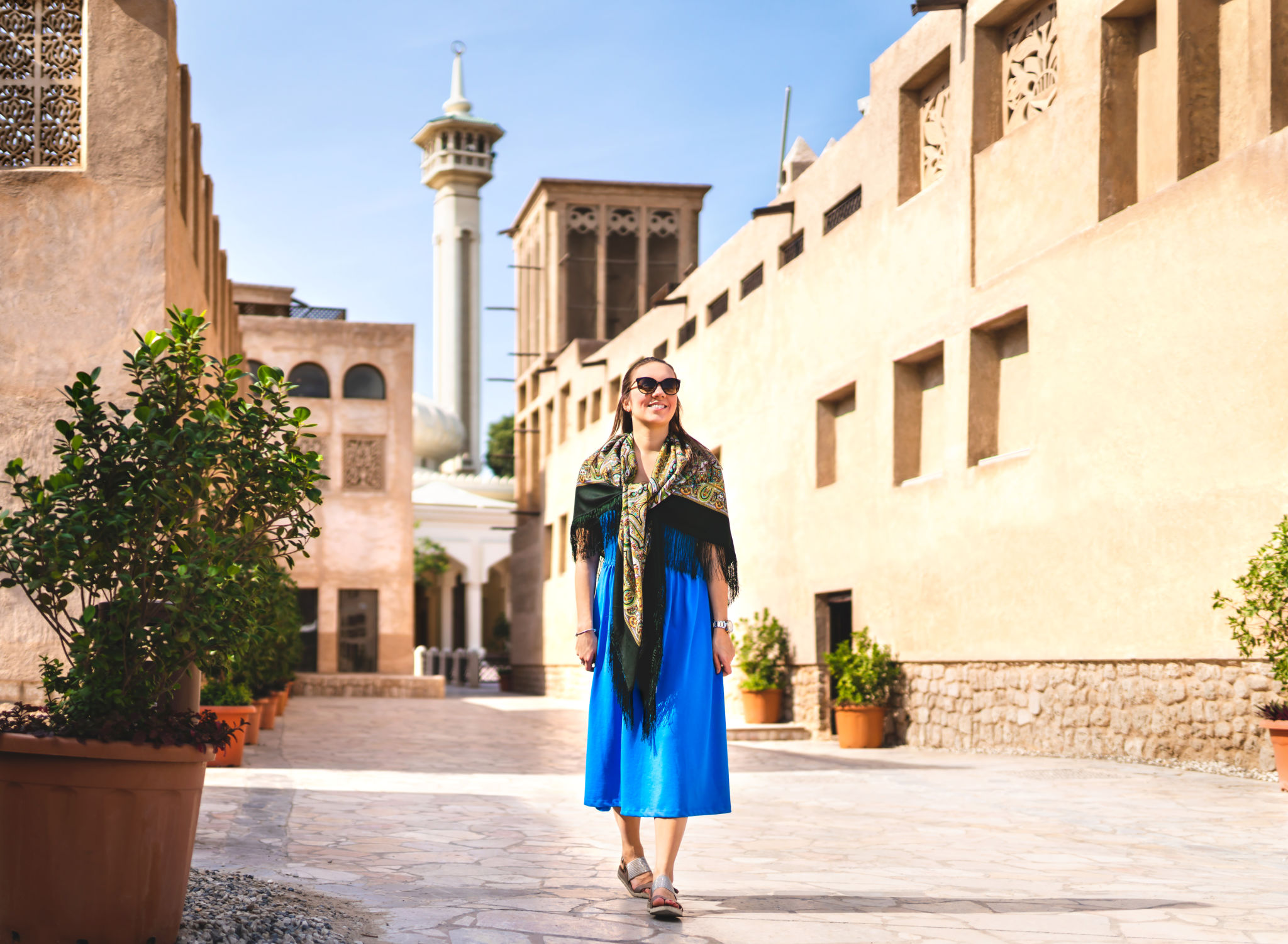 Woman walking in old Dubai, UAE. Traditional Arab street and mosque. Female tourist in historical Al Fahidi neighbourhood wearing dress. Tourism in heritage district. Happy vacation. Woman walking in old Dubai, UAE. Traditional Arab street and mosque. Female tourist in historical Al Fahidi neighbourhood wearing dress. Tourism in heritage district. Happy vacation.