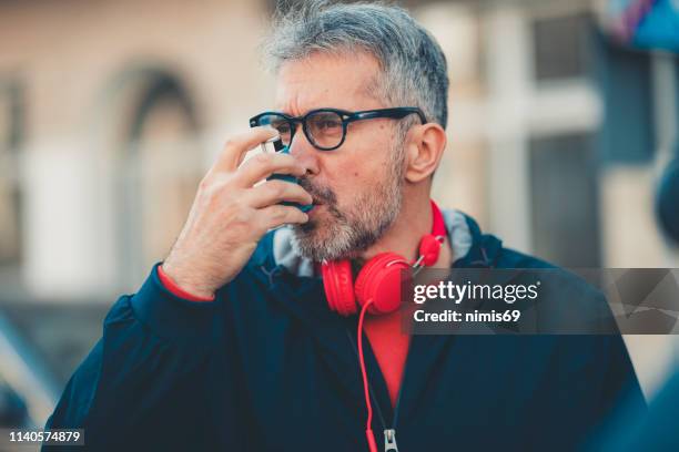 man using an asthma inhaler - copd stock pictures, royalty-free photos & images