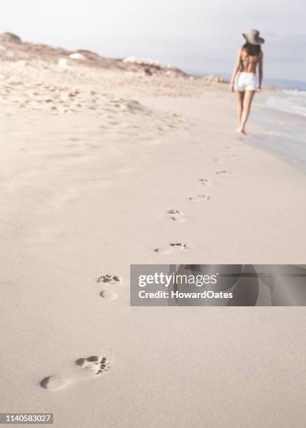 mujer caminando en la playa dejando huellas en la arena - formentera fotografías e imágenes de stock