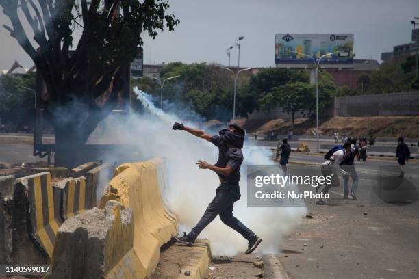 An anti-government protester throws Molotov cocktails during clashes with security forces in the surroundings of La Carlota military base in Caracas...