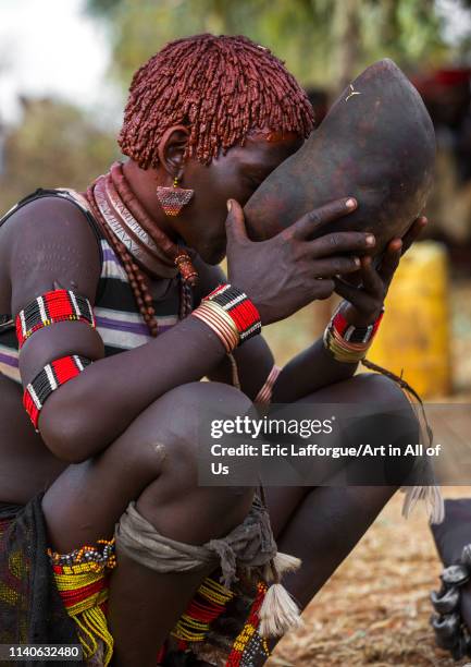 Bashada tribe woman drinkinf alcohol during a bull jumping ceremony, Dimeka, Omo valley, Ethiopia"n on December 28, 2013 in Dimeka, Ethiopia.