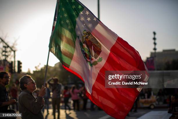 Man carries a U.S.flag and a flag of Mexico together as people march and rally on May Day, also known as International Workers Day, on May 1, 2019 in...