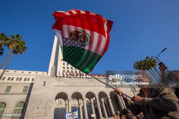 Man carries a U.S.flag and a flag of Mexico together as people march and rally on May Day, also known as International Workers Day, on May 1, 2019 in...