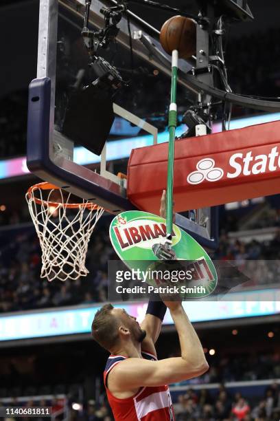 Sam Dekker of the Washington Wizards uses a floor mop to dislodge the basketball from the backboard against the San Antonio Spurs during the first...