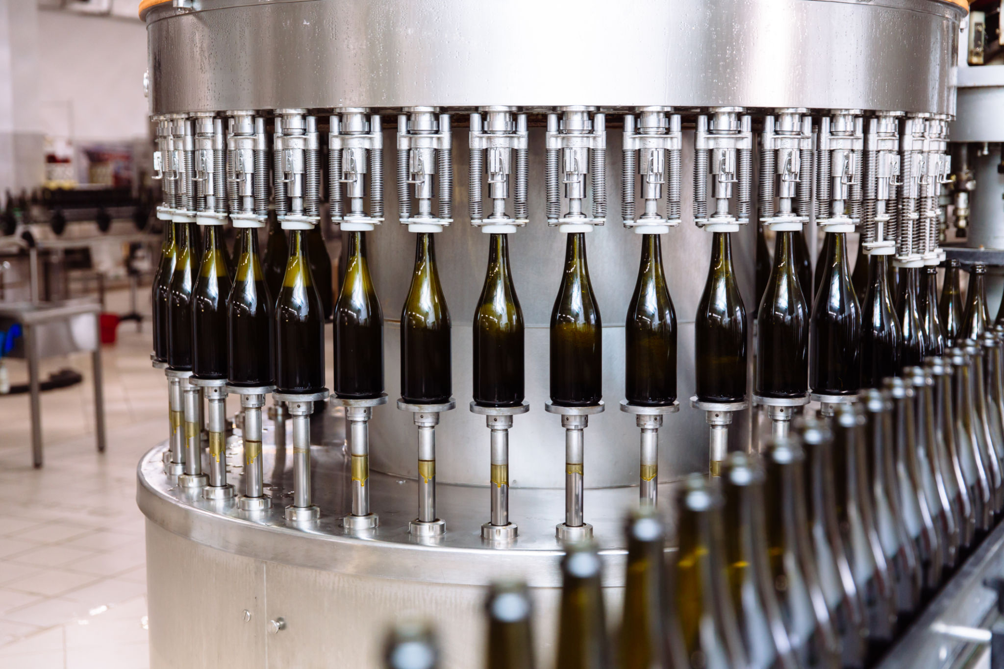 Glass bottles on the automatic conveyor line at the champagne or wine factory. Plant for bottling alcoholic beverages Glass bottles on the automatic conveyor line at the champagne or wine factory. Plant for bottling alcoholic beverages