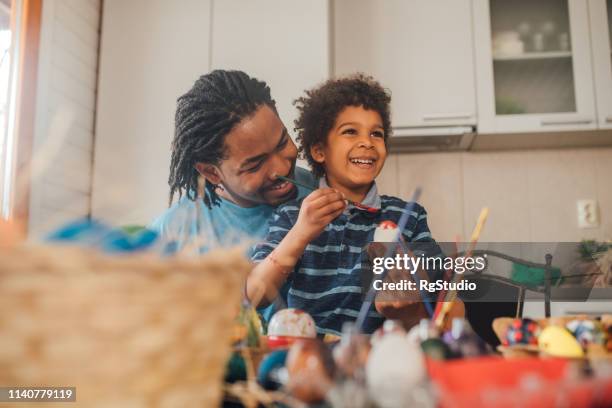 young man decorating easter eggs with his son - child craft stock pictures, royalty-free photos & images