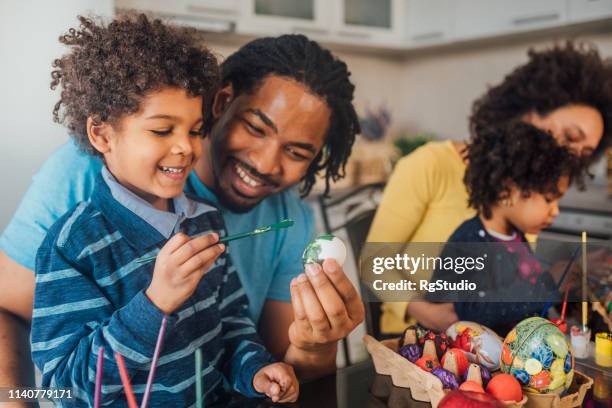 fröhliche familie schmückt ostereier - happy easter mom stock-fotos und bilder