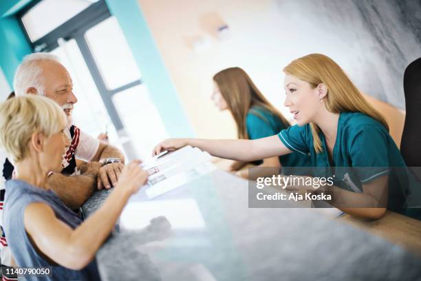 pareja de ancianos haciendo una cita con el médico. - recepcionista fotografías e imágenes de stock