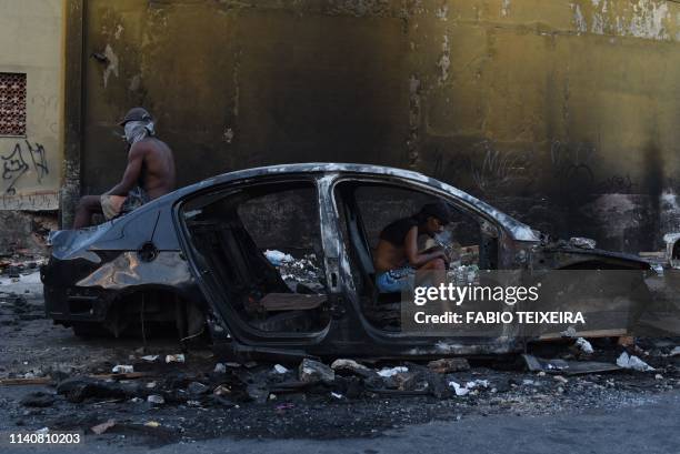 Crack addict smokes crack in a disused and burnt out car in the Sem Terra favela in Complexo da Mare, Rio de Janeiro, on April 25, 2019.