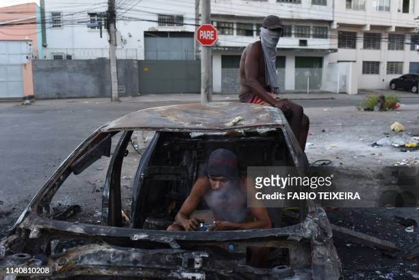Crack addict smokes crack in a disused and burnt out car in the Sem Terra favela in Complexo da Mare, Rio de Janeiro, on April 25, 2019.