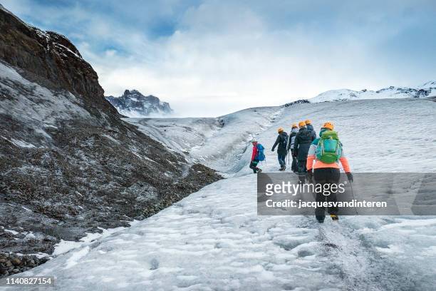 pequeño grupo de turistas que caminan en el skaftafellsjokull (glaciar) en el sur de islandia - skaftafell fotografías e imágenes de stock