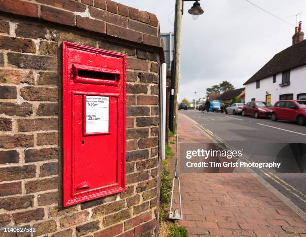 red british village post box in a brick wall - openbare brievenbus stockfoto's en -beelden