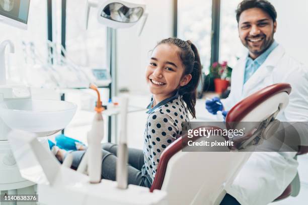 chica sonriente sentada en la silla de un dentista - odontopediatría fotografías e imágenes de stock