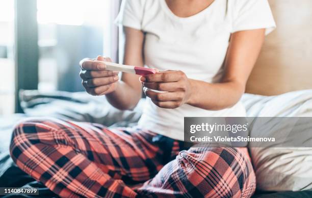 sad young woman with pregnancy test at home - ovulation stock pictures, royalty-free photos & images