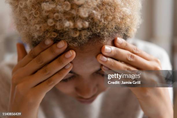 woman with headache rubbing forehead - headache stock-fotos und bilder