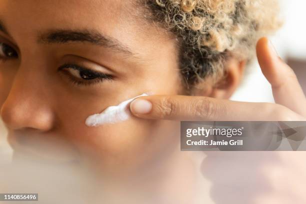 young woman applying moisturizer - creme stock-fotos und bilder