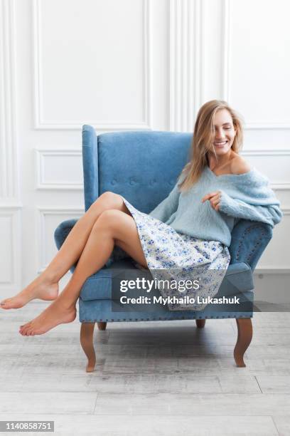 young woman sitting in blue armchair - white skirt stock pictures, royalty-free photos & images