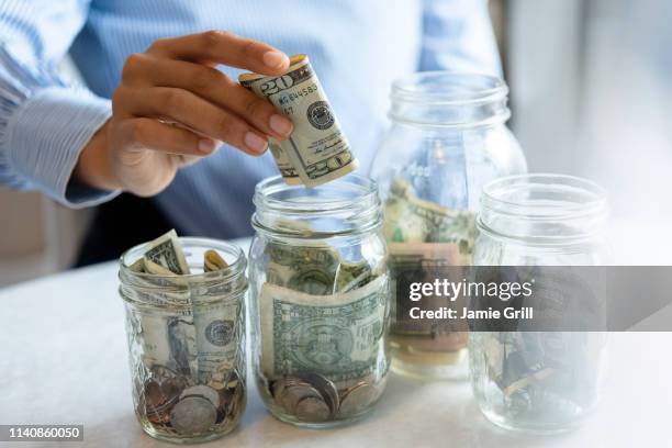 hand of woman putting money in jar - jar stock pictures, royalty-free photos & images