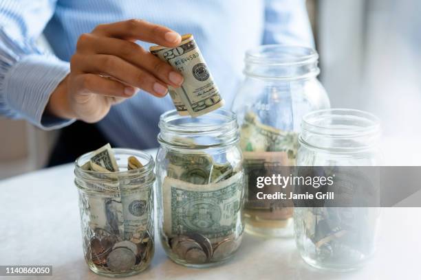 hand of woman putting money in jar - african american money stock pictures, royalty-free photos & images