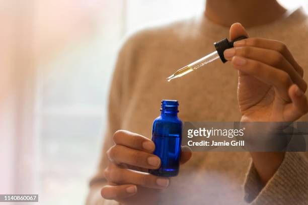 woman's hand holding pipette and bottle of aromatherapy oil - homeopathic medicine 個照片及圖片檔