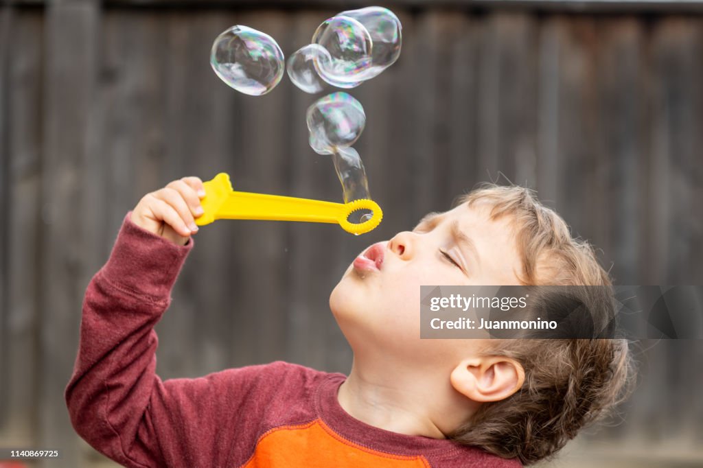 Tre år gammal barn pojke blåser bubblor