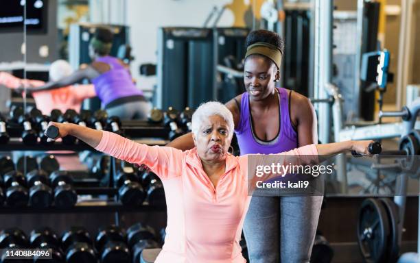 instructor de fitness afroamericano ayudando a la mujer mayor - entrenador personal fotografías e imágenes de stock