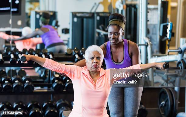 african-american fitness instructor helping senior woman - fitness instructor stock pictures, royalty-free photos & images