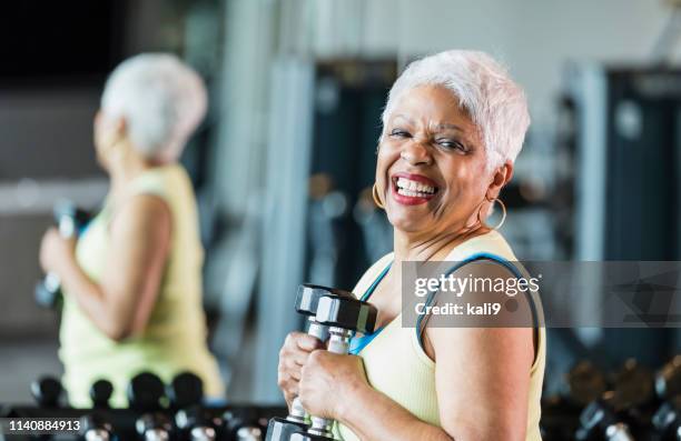 obere afroamerikanerin im fitnessstudio heben hanteln - baby boomer stock-fotos und bilder