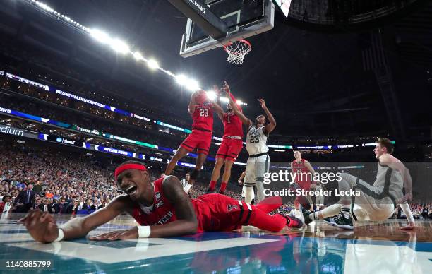 Tariq Owens of the Texas Tech Red Raiders falls on the court as Xavier Tillman of the Michigan State Spartans battles for the ball with Jarrett...