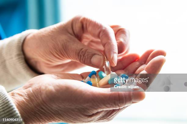 senior woman hand picking pill - hands full stock pictures, royalty-free photos & images