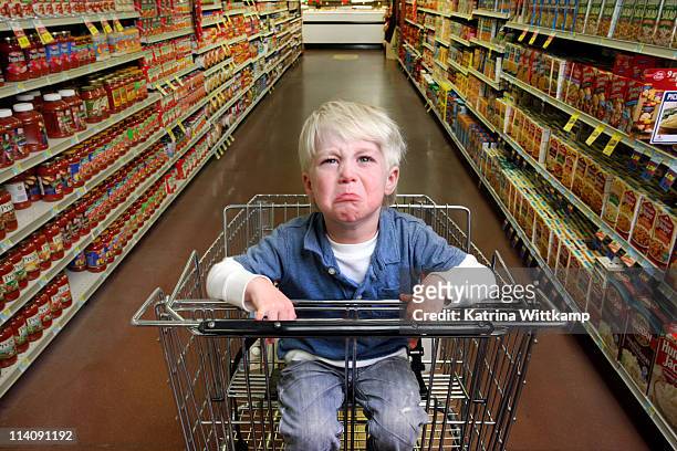 boy crying in grocery cart. - woedeaanval stockfoto's en -beelden