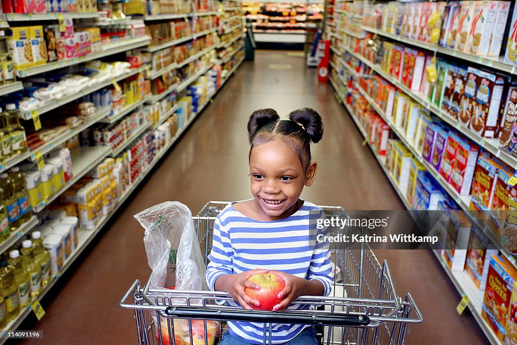 Girl sitting in grocery cart.