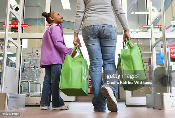 mom and daughter walking out of grocery store. - carrying groceries foto e immagini stock