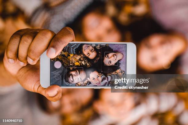 nahaufnahme der glücklichen schwarzen familie, die ein selfie mit handy in den herbstblättern. - black girl with computer stock-fotos und bilder