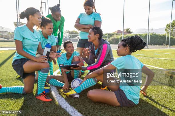 Girls soccer team listening to their female coach