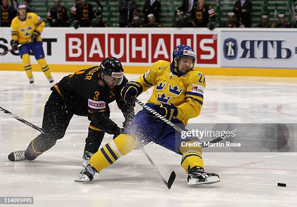 Robert Nilsson of Sweden and Justin Krueger of Germany battle for the puck during the IIHF World Championship quarter final match between Sweden and...