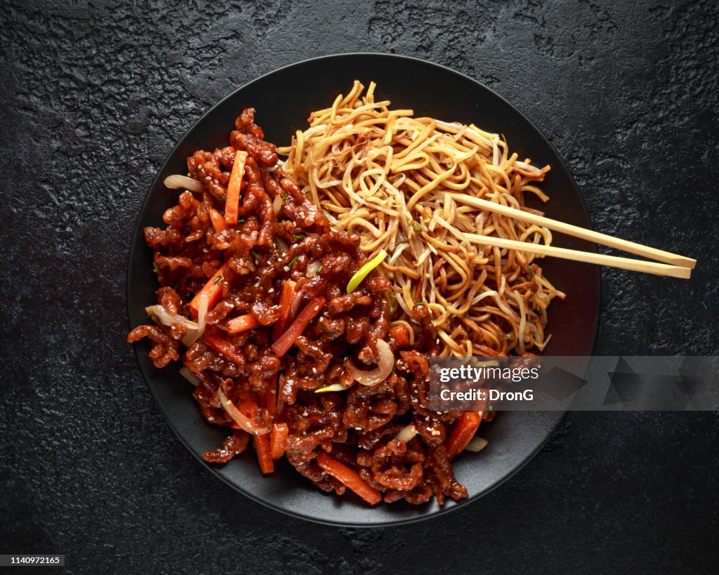 Egg noodles with bean sprouts and Crispy shredded beef on black plate