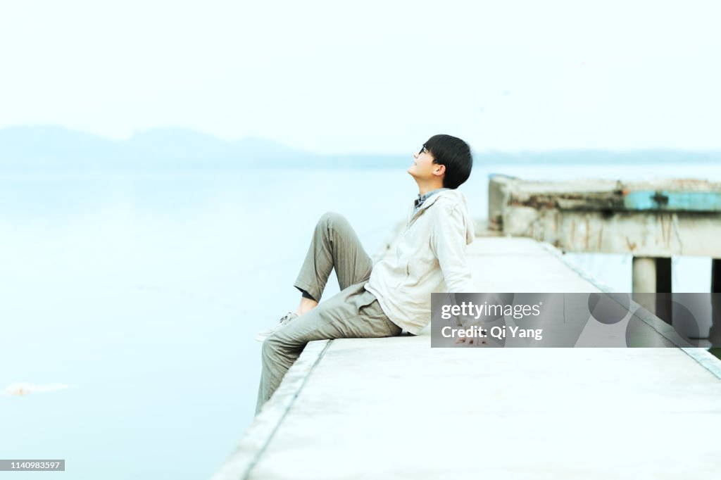 Young handsome man sitting on pier