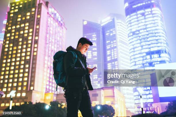 young man using cell phone on urban street at night - shanghai city life stock pictures, royalty-free photos & images